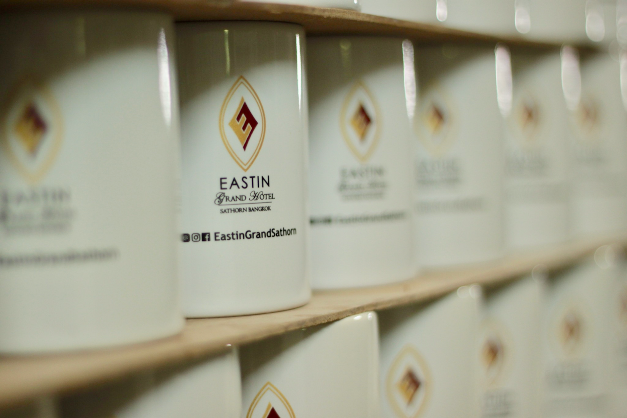 แก้วเซรามิคสกรีนโลโก้ Eastin Grand Hotel Sathorn เรียงบนชั้นในโรงงาน